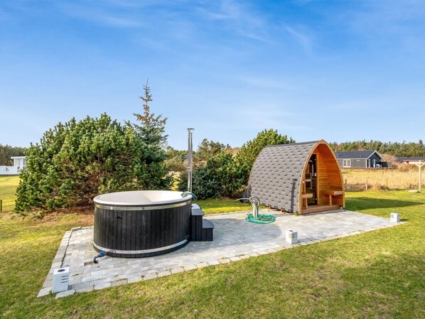 A hot tub and a wooden structure in a landscaped outdoor area.