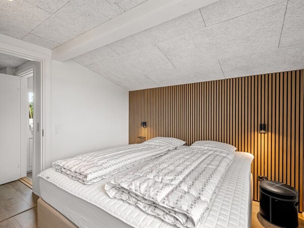 A bedroom with a bed, bedside lamps, and a wooden slat wall.