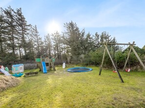 A playground with a slide, swing set, and a small house structure.