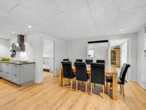 A modern kitchen with a dining area, wooden flooring, and a large window.