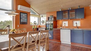 Eine moderne Küche mit Holzausstattung, einem eingebauten Ofen und einem Essbereich mit Holztischen und einer Tischplatte.