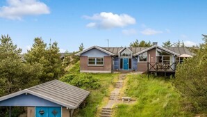 Eine zweistöckige Lodge mit blauer Tür und einer Terrasse.