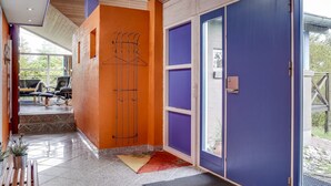 Ein modernes Interieur mit Holzboden, einer blauen Tür und einer Sitzecke mit einer Bank und Stühlen.