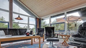 Ein modernes Wohnzimmer mit einem großen Fenster, Ledermöbeln und einem gemusterten Teppich.