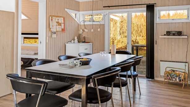 A modern dining area with a long table, black chairs, and a white cabinet. - "Thorolf" - 30km from the sea by Interhome (Toftlund)