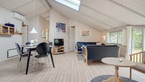 A spacious living area with a high ceiling, wooden flooring, a dining table with chairs, a sofa, a television, and artwork on the walls. - "Selver" - 250m from the sea by Interhome (Hals)