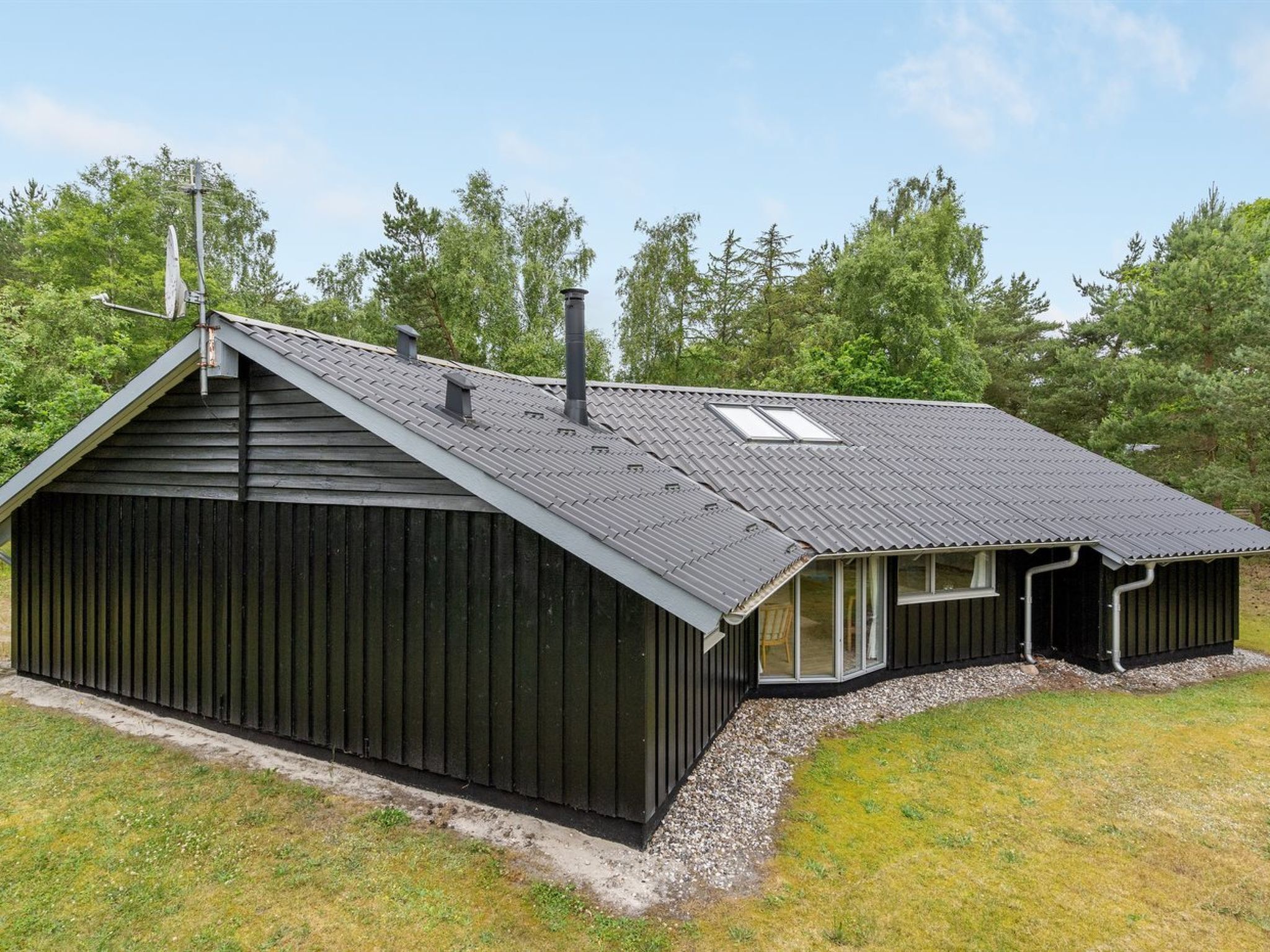 A single-story building with a sloped roof, a chimney, and a small attached structure with windows.
