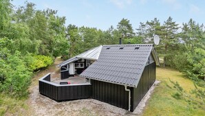A metal-roofed building with a deck, surrounded by dense greenery. - "Selver" - 250m from the sea by Interhome (Hals)