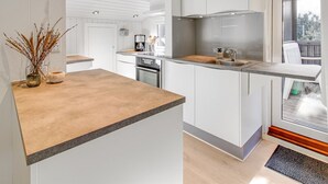 A modern kitchen with white cabinetry, a wooden countertop, and a built-in oven.