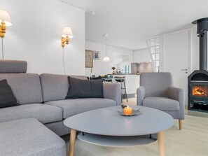 Una sala de estar moderna con un sofá gris, una mesa de centro redonda y una chimenea.