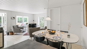 A modern dining area with a round table, chairs, and a television in the background.