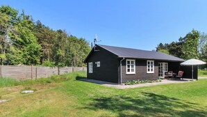 A single-story house with a dark exterior, white trim, and a satellite dish on the roof. It has a covered patio area with outdoor furniture. - "Ingalise" - 500m from the sea by Interhome (Hals)