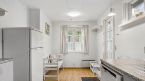 A compact kitchen with a refrigerator, a dining table, and a window with curtains. - "Ingalise" - 500m from the sea by Interhome (Hals)