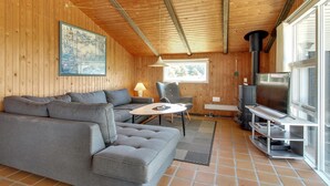 A cozy living room with a gray sectional sofa, a small round table, a chair, a TV, and a fireplace. - "Alaia" - 1km from the sea by Interhome (Vejers Strand)