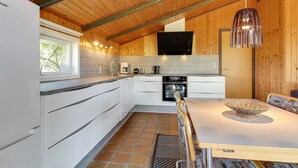 A modern kitchen with white cabinets, a large island, and a wooden ceiling. - "Alaia" - 1km from the sea by Interhome (Vejers Strand)