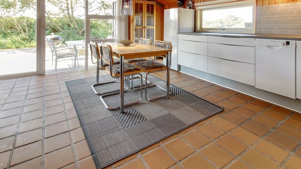 A modern kitchen with a wooden ceiling, a dining area with a table and chairs, and a view of the outdoors through large windows. - "Alaia" - 1km from the sea by Interhome (Vejers Strand)