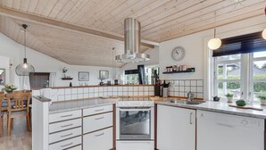 Una cocina moderna con armarios de madera, horno empotrado y un amplio ventanal que proporciona luz natural.