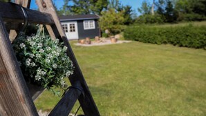 A wooden swing set with a hanging flower basket in a grassy yard with a house in the background. - "Harre" - 300m from the sea by Interhome (Rudkøbing)