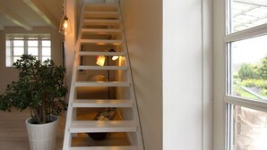 A white staircase with built-in lighting, a potted plant, and a view of a garden through a window. - "Harre" - 300m from the sea by Interhome (Rudkøbing)