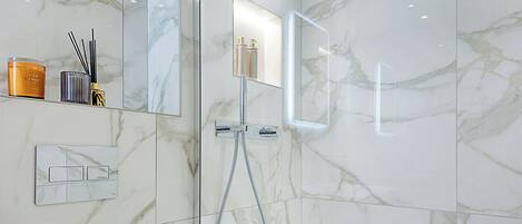 A modern bathroom with a glass-enclosed shower, a white toilet, and a bathtub.