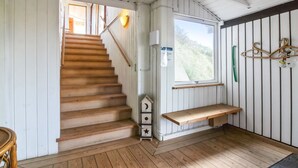 Un escalier en bois mène à une pièce où se trouvent un banc et une fenêtre donnant sur un espace verdoyant.