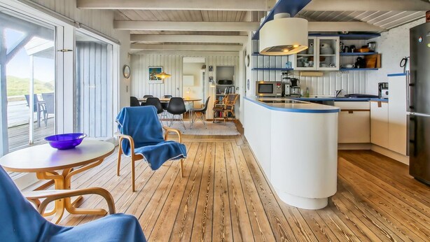 Une cuisine moderne dotée d’un îlot central, de planchers en bois et d’un coin repas avec une table et des chaises.