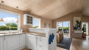 Una cocina moderna con armarios blancos, lavavajillas integrado y ventana con vistas a zonas verdes.