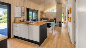Eine moderne Küche mit einer großen Kochinsel, Holzschränken und einem Essbereich mit Tisch und Stühlen.