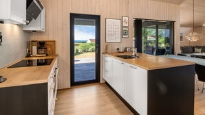 Eine moderne Küche mit Holzausstattung, einer großen Kochinsel und Blick durch die Tür.