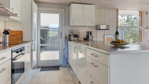 Una cocina moderna con armarios blancos, una isla grande y vistas a través de un ventanal corredero.