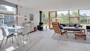 Un interior moderno con suelo de madera, paredes blancas, un ventanal grande y una chimenea.