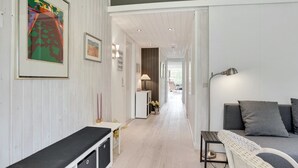 Un interior moderno con una paleta de colores blanco y gris, que incluye un sofá, un banco y un comedor con mesa y sillas.