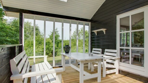 A covered patio with white wooden furniture, including benches and a table, set against a backdrop of greenery. - "Gaetana" - 1.6km from the sea by Interhome (Hals)
