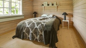 A cozy bedroom with a wooden floor and walls, a bed with a patterned bedspread, two bedside lamps, and a window with a view of greenery. - "Gaetana" - 1.6km from the sea by Interhome (Hals)