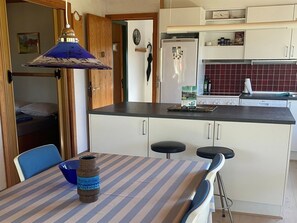 Una cucina compatta con frigorifero, microonde e fornello. C'è un'area pranzo con tavolo e sedie.