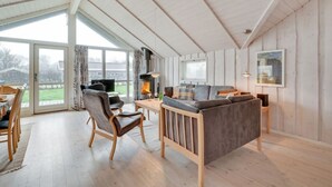 A spacious living room with a large sofa, a dining table, and a fireplace.