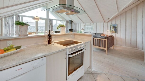 A modern kitchen with white cabinetry, a Bosch dishwasher, a stainless steel oven, and a glass range hood.