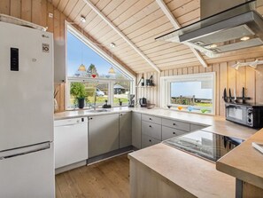 Eine moderne Küche mit eingebautem Geschirrspüler, Mikrowelle und Herd. Zwei Fenster bieten Ausblick ins Freie.