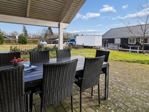 Eine Terrasse im Freien mit überdachter Sitzgelegenheit, einem Tisch und Stühlen.