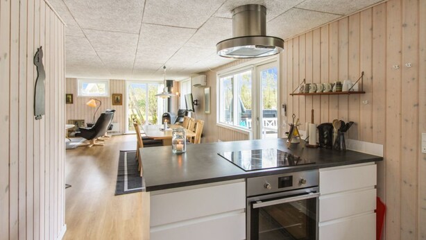 Une cuisine moderne dotée d’un îlot central, d’un four encastré et de panneaux muraux en bois.