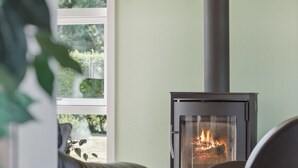 Una habitación acogedora con una chimenea moderna, un sofá de cuero cómodo y vistas a la vegetación.