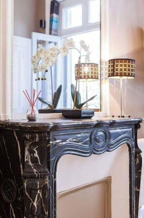 A marble fireplace with a vase of white orchids and a floor lamp. - Studio Wagram /etoile / Champs Elysées à Pied !! (Paris)
