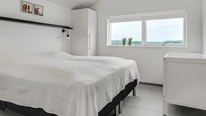 Un dormitorio moderno con una cama grande, una mesita de noche, una ventana con vistas y una lámpara en el techo.