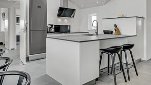 Una cocina moderna con una isla central, horno empotrado y televisor de pantalla plana.