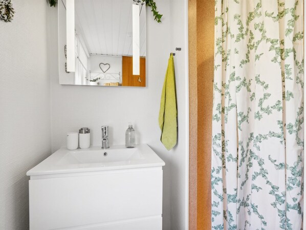 A bathroom with a white sink, a mirror, and a green towel hanging on the wall.