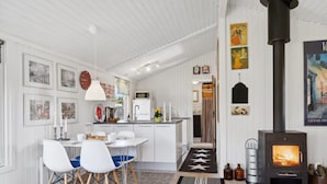 A modern kitchen with white cabinetry, a central island, and a black wood-burning stove. - "Hellevi" -  from the sea by Interhome (Hals)