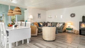 A modern living room with a dining area, a sofa set, a round ottoman, and a fireplace.