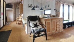 A cozy room with a wooden ceiling, a black chair with a star pillow, a wooden cabinet, and a window with curtains.