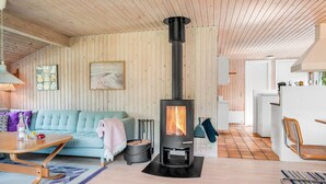 A cozy living room with a wooden ceiling, a sofa, a table with drinks, and a wood-burning stove. - "Myrna" - 300m from the sea by Interhome (Hals)