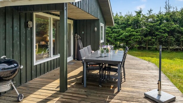 A wooden deck with a table and chairs, a barbecue grill, and a covered outdoor seating area. - "Myrna" - 300m from the sea by Interhome (Hals)
